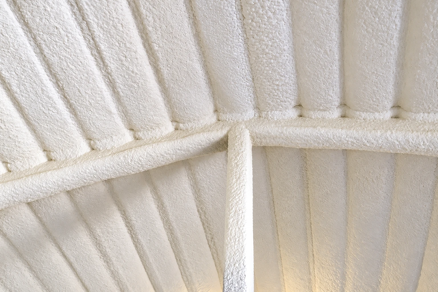 White spray foam insulation coats the roof and beams, forming a thick, bumpy layer.